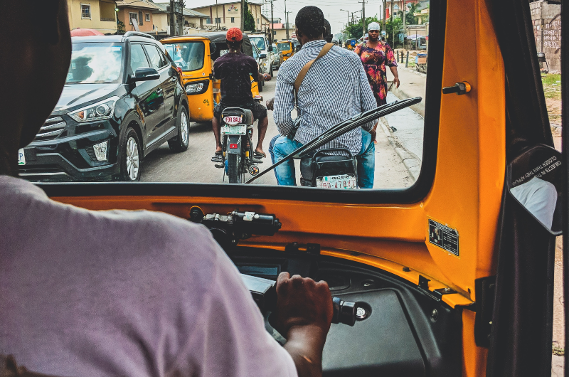 Image of a man driving a TukTuk through heavy traffic in Africa